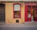 a yellow building with a red door and window